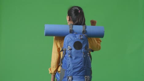 woman with backpack and yoga mat on a green screen