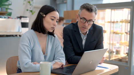 an business woman showing documents on the laptop to a business man at a meeting in a coffe shop 1