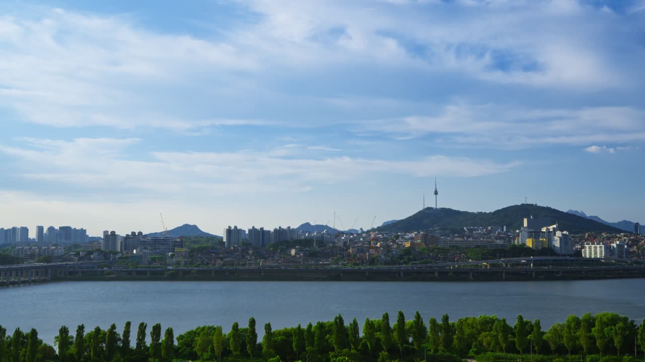 Beautiful aerial view of the iconic Seoul cityscape featuring Namsan Tower, the lush Hangang Park, and traffic on the Gangbyeonbuk-ro expressway