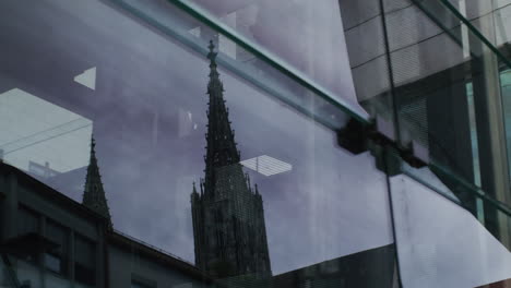 the famous ulmer münster reflecting in a glass window, camera tracks to the right