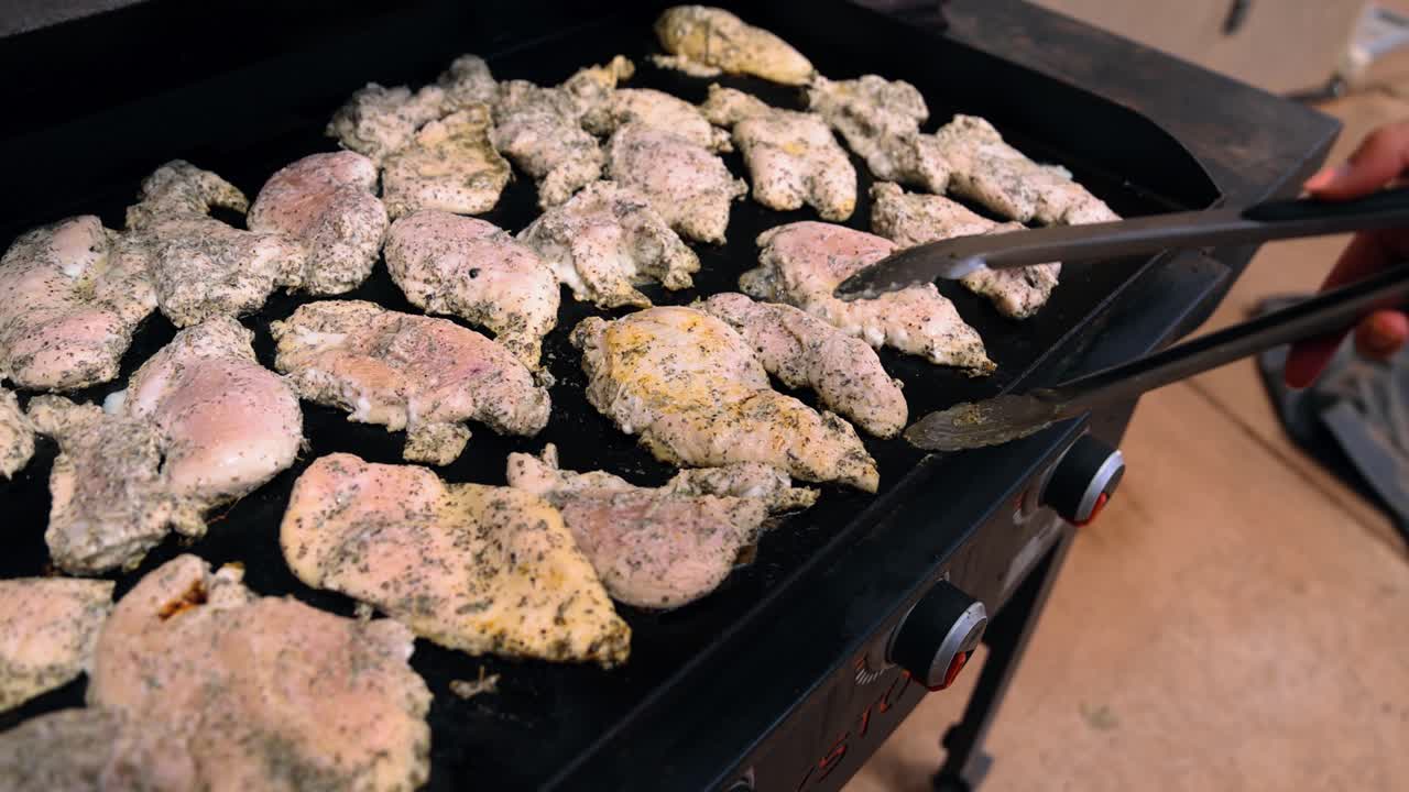 Person's Hand Cooking Chicken Fillet On Flat Griddle Pan. - closeup shot