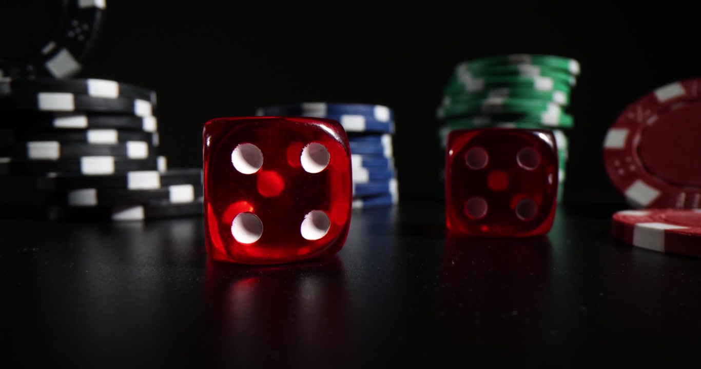 Red crystal dice and casino chips stacked on black table