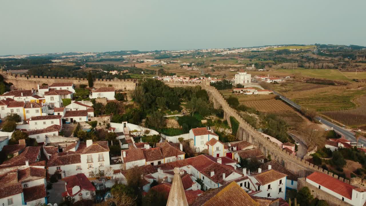 Ripresa aerea cinematografica a Óbidos, all'interno della città fortificata, con ripresa aerea sui tetti e sorvolo della Chiesa di Santa Maria, uscendo dalle mura per rivelare l'intera città medievale e le colline circostanti