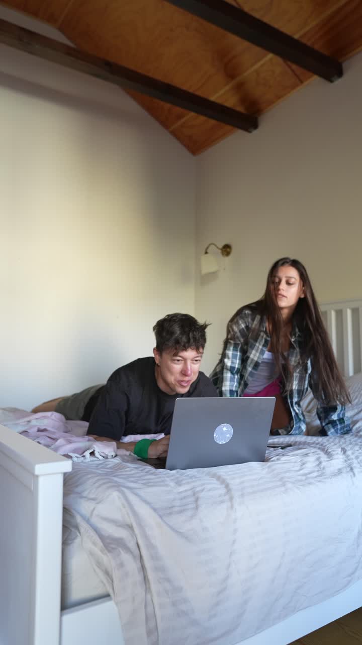 Couple relaxing in bed, using a laptop