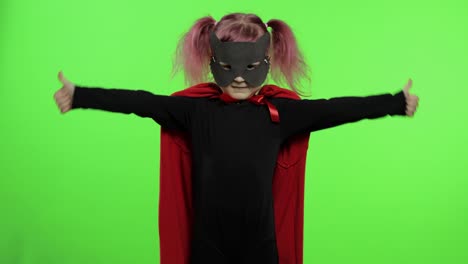 funny child girl in costume and mask plays super hero. national superhero day