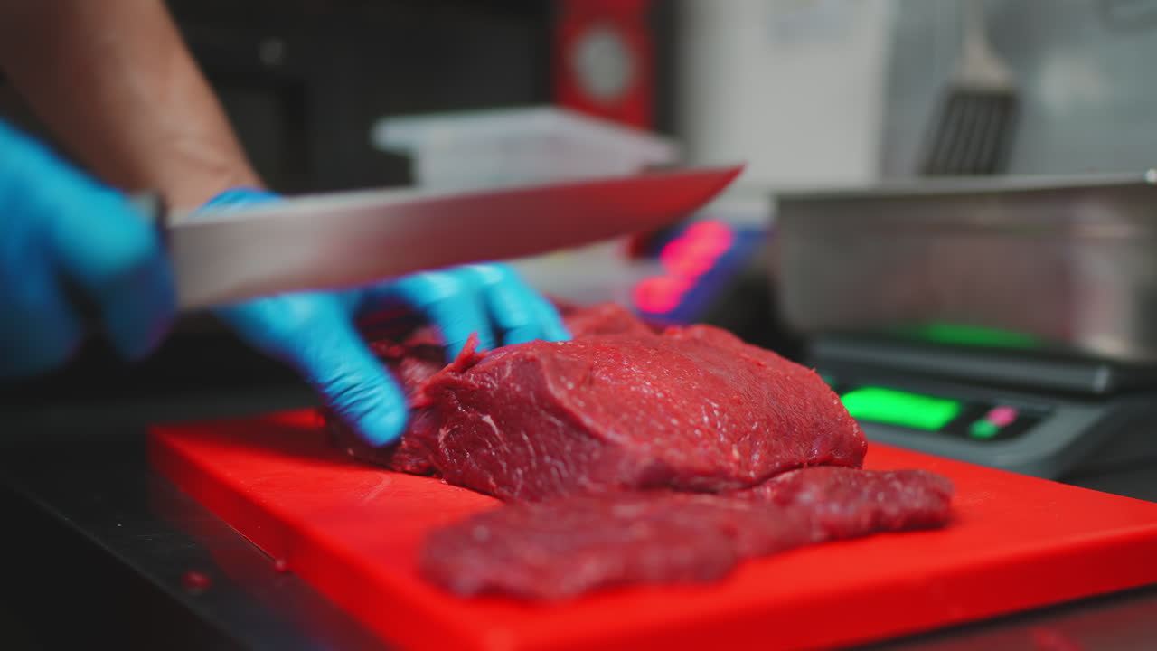 Chef Slicing Raw Beef on a Red Cutting Board