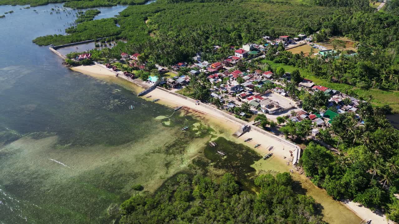 Stunning aerial pullback of coastal village community amid lush greenery at tropical island Catanduanes, Bicol, Philippines.