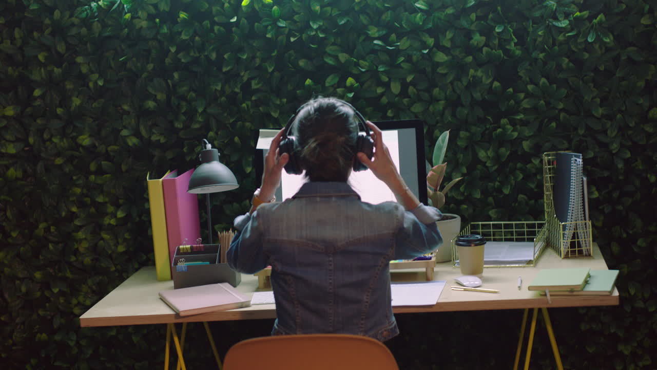 молодая бизнес-женщина, работающая допоздна, использующая компьютер, просматривающая интернет, планирующая творческую стратегию стартапа, слушающая музыку, носящая наушники в офисе ночью