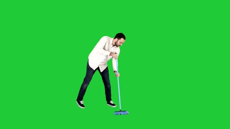 young man cleaning floor with brush on a green screen, chroma key