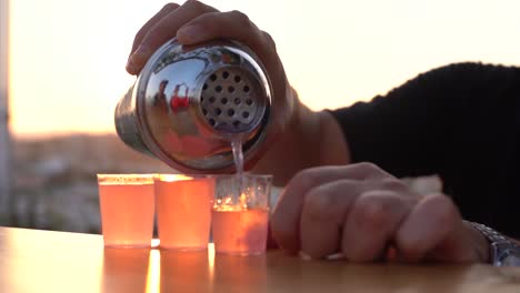 vertiendo tragos al aire libre contra un atardecer de fondo