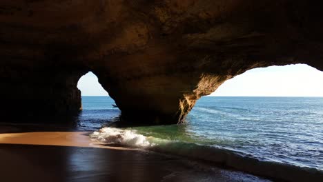 inside benagil cave. straight line drone shot. boat passing entrance.