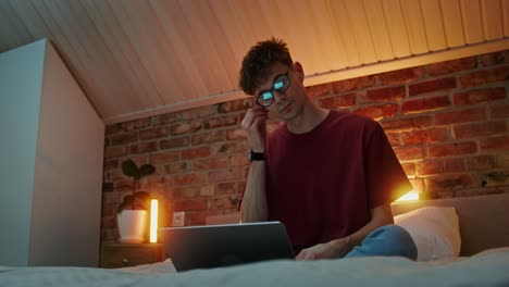 hombre trabajando en una computadora portátil en un dormitorio por la noche