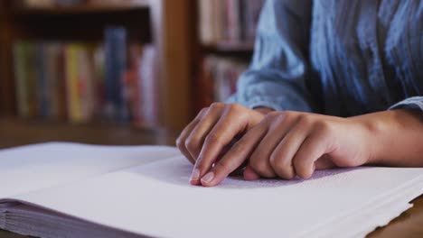 Asiatische-Studentin-Sitzt-Und-Berührt-Eine-Seite-Eines-Braille-Buches-In-Der-Bibliothek