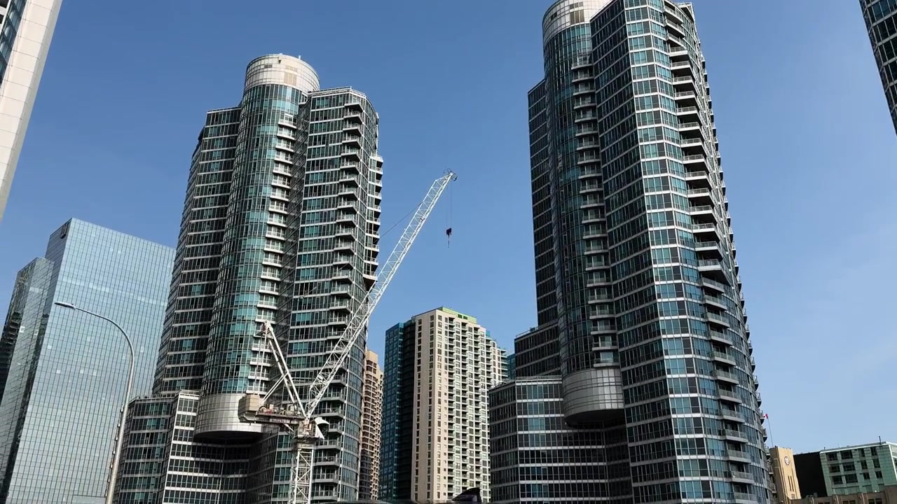 Moderni grattacieli e gru edili sotto un cielo azzurro limpido a Toronto