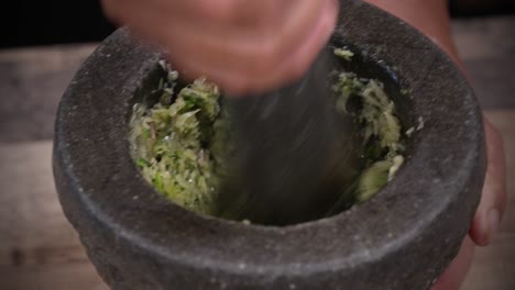 pounding fresh ingredients with stone mortar and pestle, fresh paste cooking close up