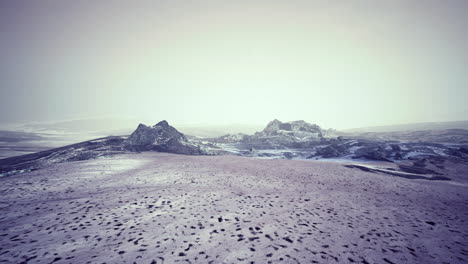 vast icy landscape with rugged mountains under a cloudy sky
