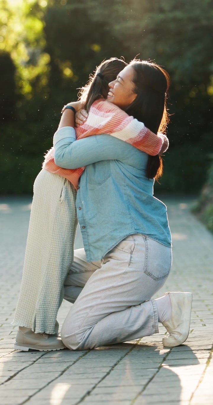 Madre e figlia che si abbracciano all'aperto nella luce dorata del tramonto