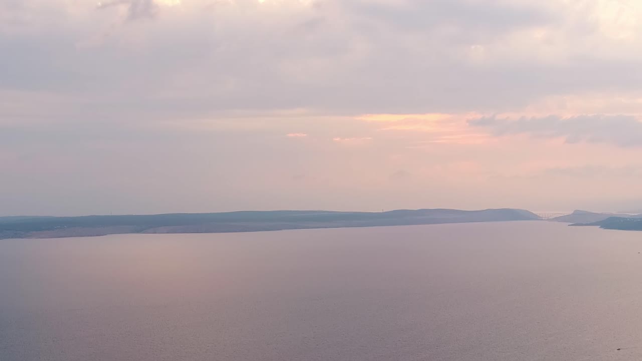 Solnedgang over det rolige vannet i en bukt i Kroatia med myke farger