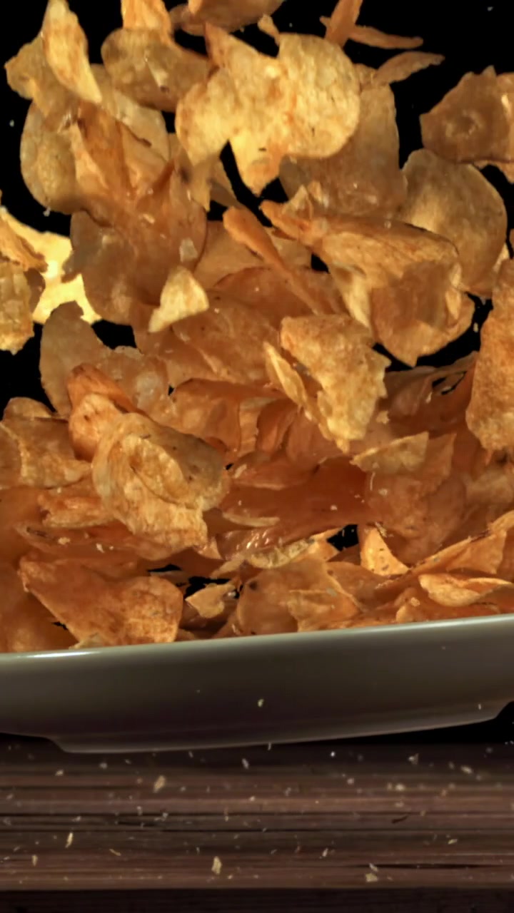 Golden Potato Chips Exploding from a Plate in Slow Motion