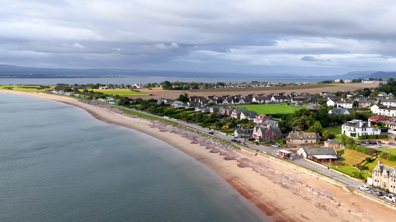 Drönare glider fram över Rosemarkies kustlinje och avslöjar kustby, sandstrand och landsbygdslandskap