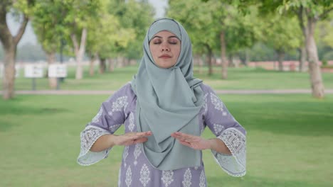 happy muslim woman doing yoga in park