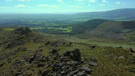 Vista-De-La-órbita-Aérea-Del-Afloramiento-Rocoso,-La-Línea-De-La-Cresta-Y-El-Valle-Con-Vista-A-La-Distancia-Sobre-El-Sur-De-Las-Tierras-De-Cultivo-Y-El-Valle-De-Irlanda