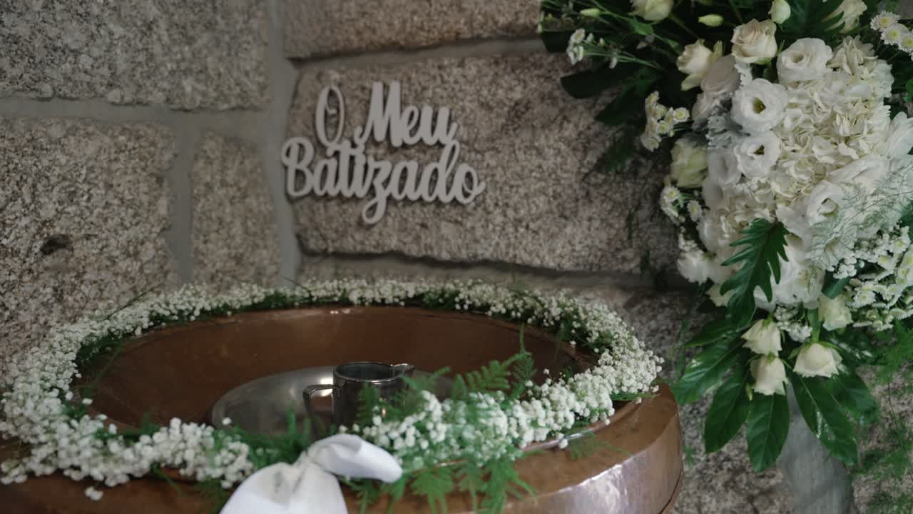 Allestimento floreale per battesimo con fonte battesimale decorata e fiori bianchi
