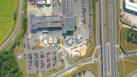 Aerial-view-of-the-logistics-park-with-warehouse,-loading-hub-and-many-semi-trucks-with-cargo-trailers-standing-at-the-ramps-for-load-unload-goods-at-sunset