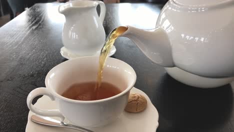 Pouring-hot-tea-and-milk-into-a-porcelain-cup
