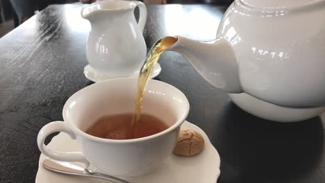 pouring hot tea and milk into a porcelain cup