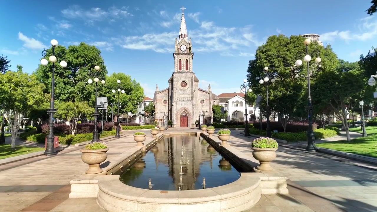 Chiesa storica in pietra con torre dell'orologio riflessa nello stagno del giardino in una giornata di sole
