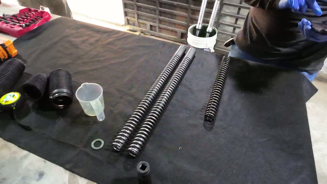 Technical process of motorcycle fork suspension rebuild. Focus on new springs, specialized tools, and fluid application