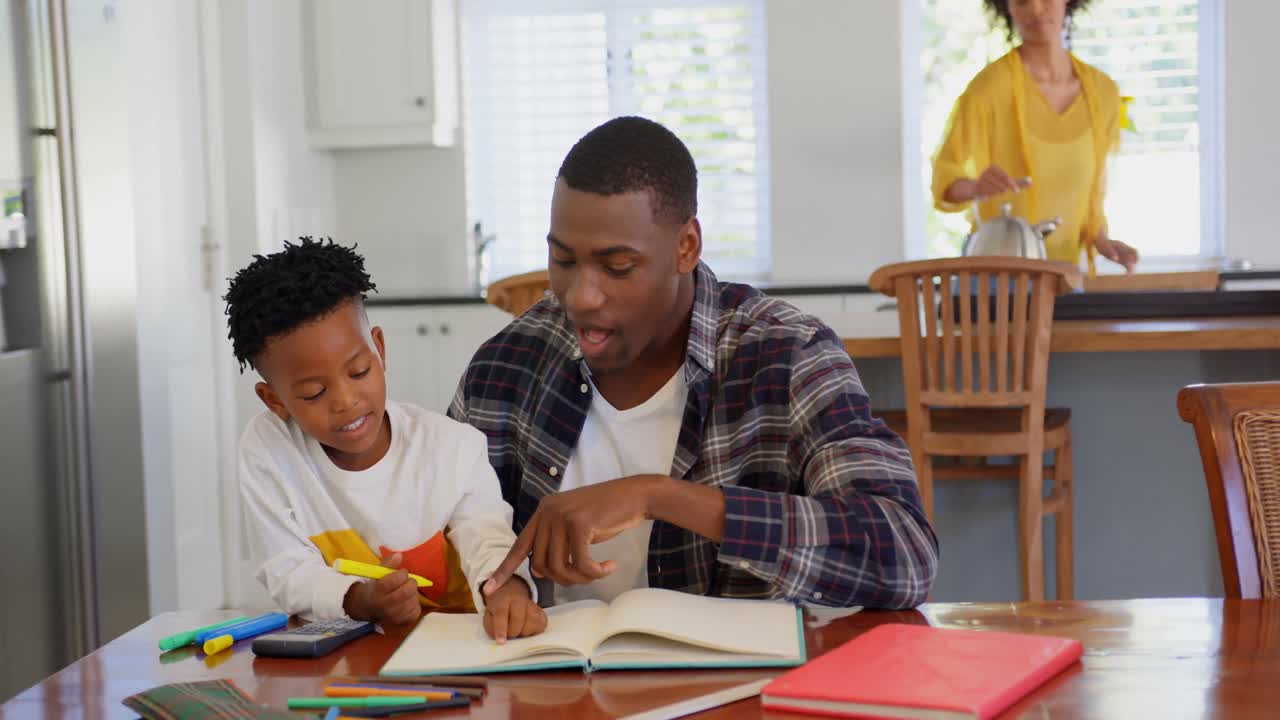 Front view of black father helping his son with homework at comfortable home 4k