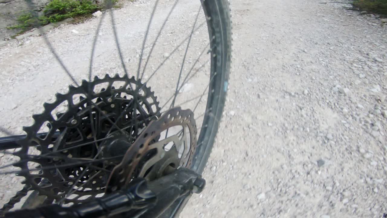 Close-up action shot of bicycle wheel skidding down gravel mountain trail