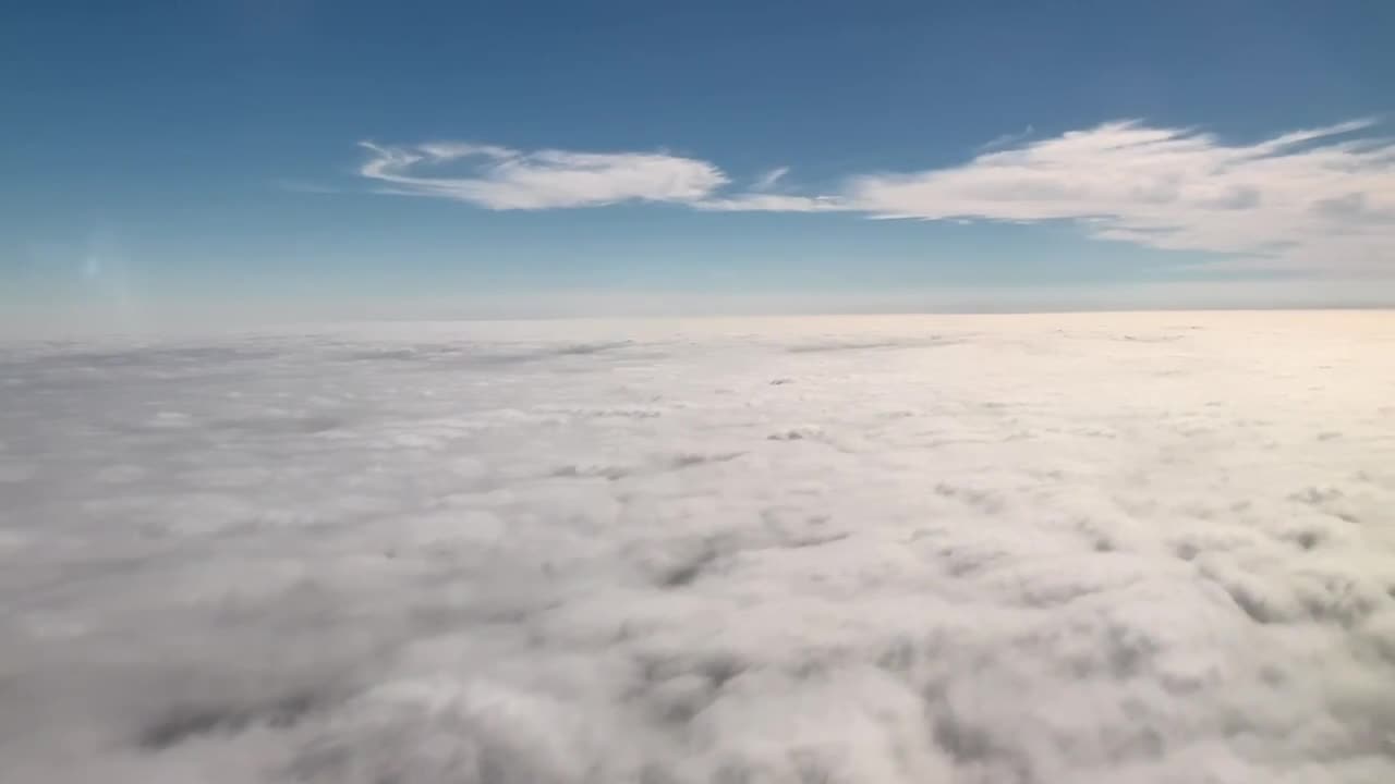Flying over white puffy clouds on a clear blue sky day