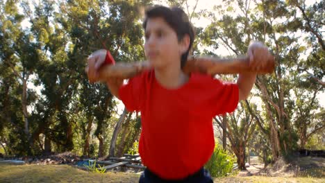 determined boy exercising with log in boot camp