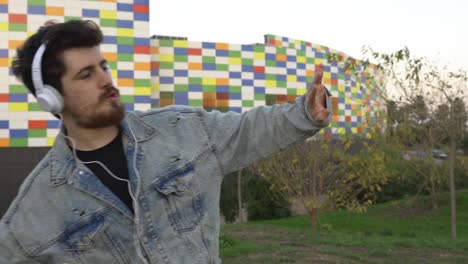 hombre feliz bailando con auriculares y teléfono móvil en la mano