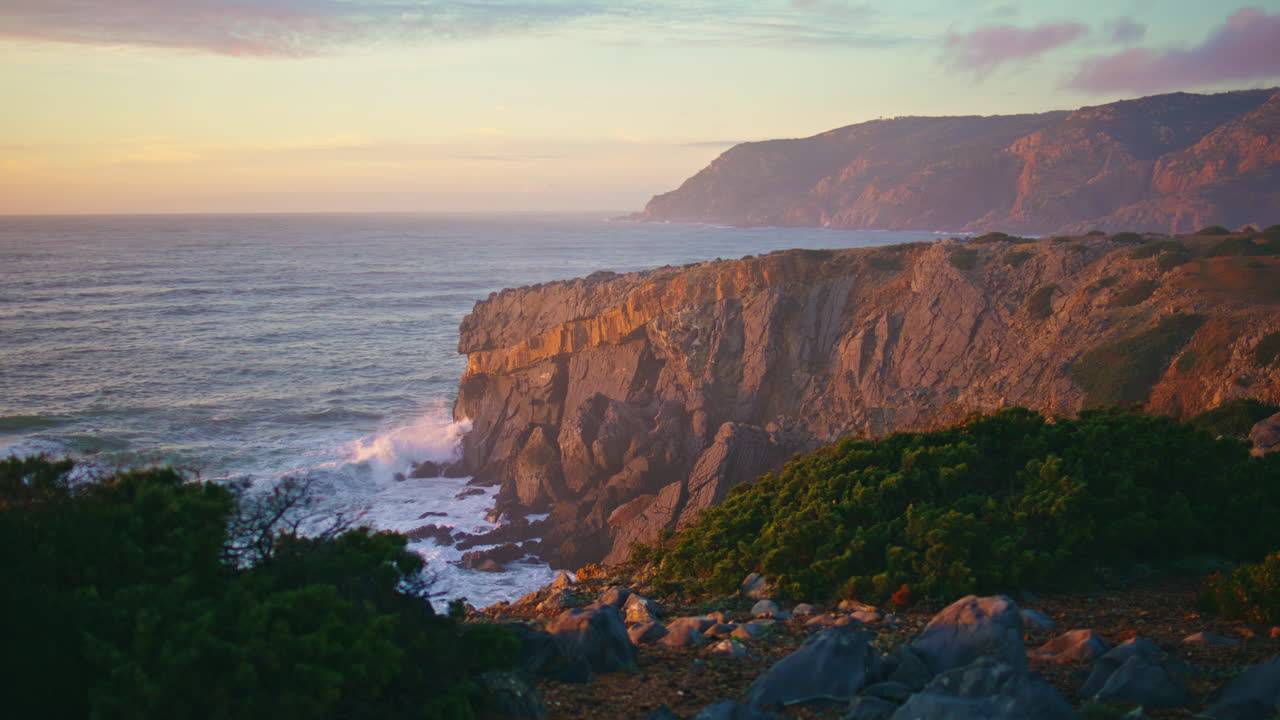 drone paisaje paisajístico de la costa en la luz del atardecer. las olas del océano chocan contra el terreno rocoso