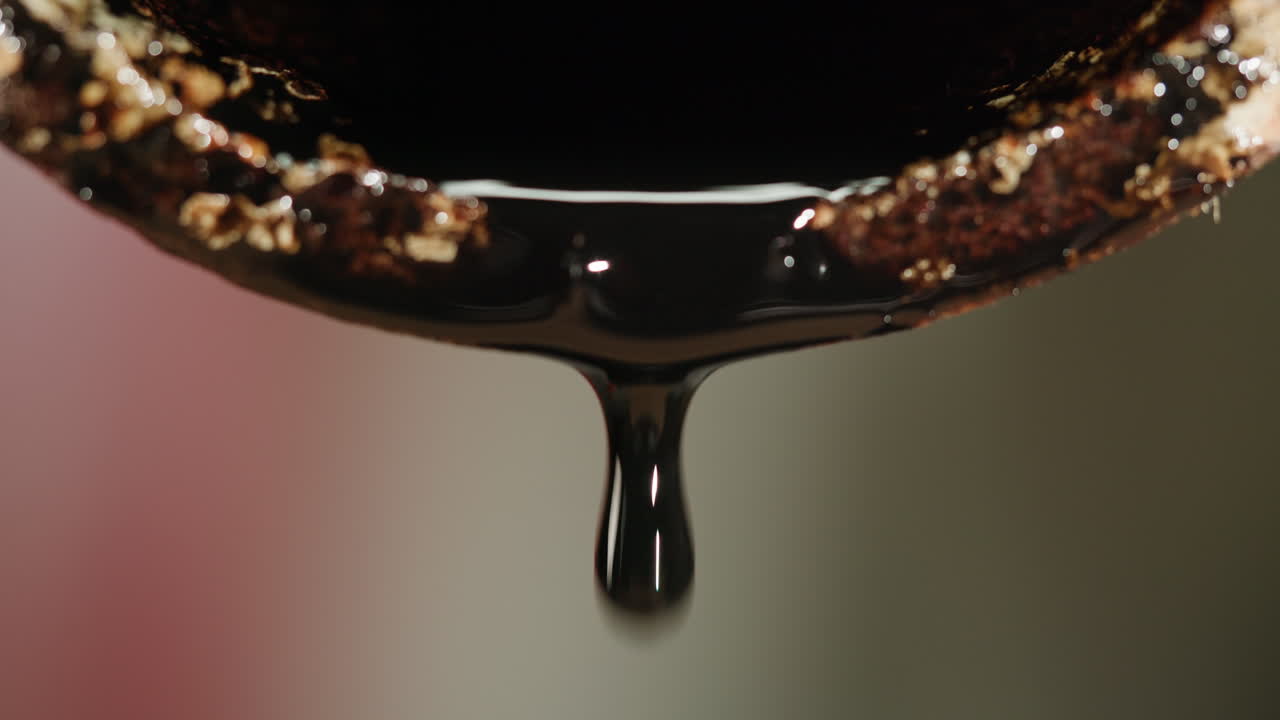 Close-up of a dark liquid dripping from a container