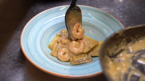 añadiendo ravioli con camarones en crema agria en un plato
