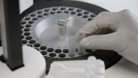 laboratory scientist places two test tubes in the chemical analyser for testing