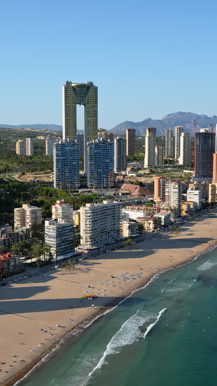 Aerial drone view of the buildings along the coastline and the sea in Benidorm, Spain in daylight. Vertical
