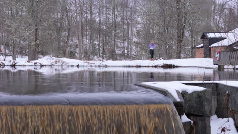 an ice bathing woman starts to strip off before her plunge into an icy pond