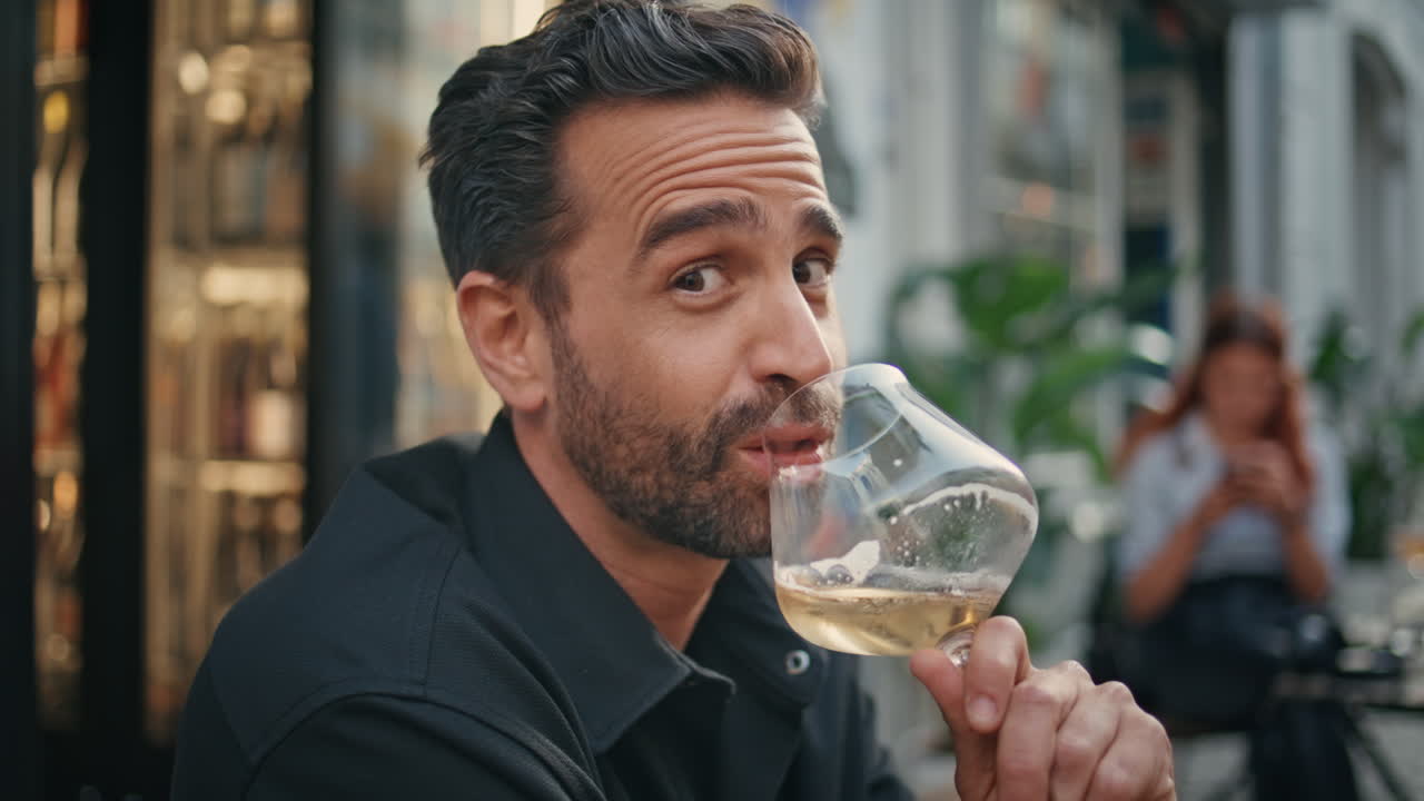 Ritratto di un uomo affascinante che beve un bicchiere di vino in un bar all'aperto. Uomo sorridente che guarda la fotocamera.