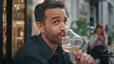 portrait hot macho drinking wineglass at street bar. smiling man looking camera