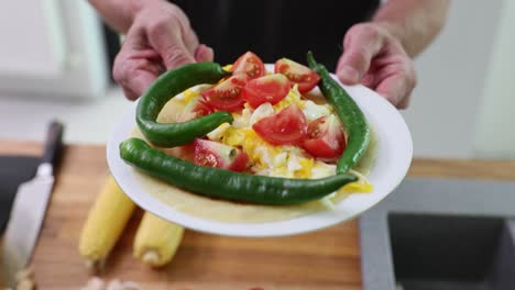 person holding a plate with scrambled egg and vegetable taco