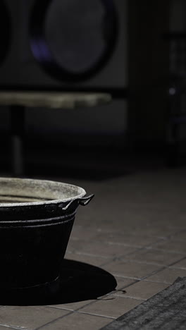 bucket sits alone in a dimly lit laundry room during late hours