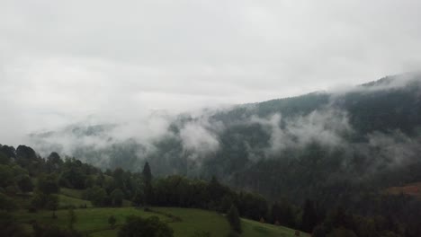 Drone-flying-above-misty-mountains-in-Romania,-Matisesti