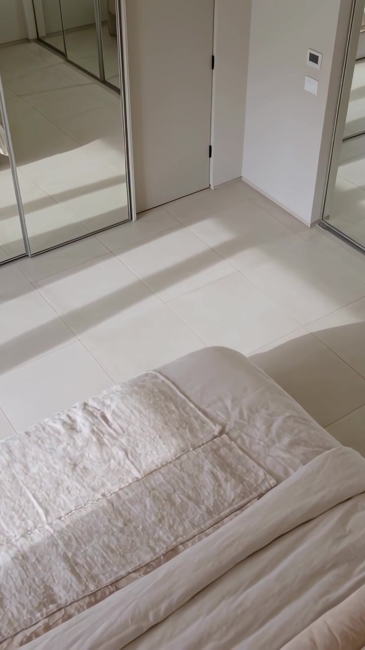 Video verticale: Luce solare che scivola dalle persiane attraversando il pavimento della camera da letto, passando sopra il letto e lo specchio