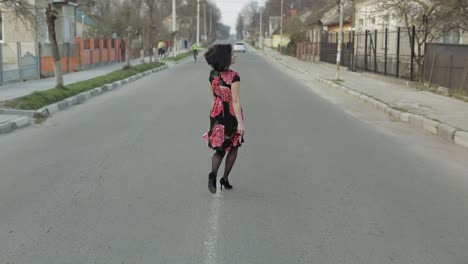 Attractive-young-woman-in-a-dress-with-flowers-walking-on-the-highway